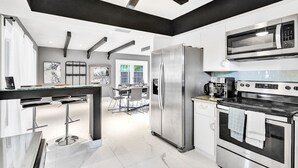 Eine moderne Küche mit Edelstahlgeräten, einer Bar und Blick in den Essbereich.