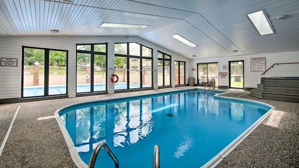 Ein Innenpool mit großen Glaswänden, Fliesenboden und einer Decke mit Oberlichtern.