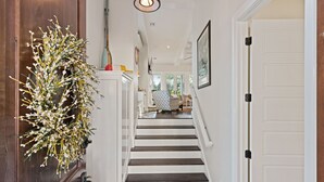 A staircase with white railings and dark wooden steps leading to a room with a patterned rug. - Shore am Happy located at the 8th Street Beach Entrance, sleeps 12 w/ large Pool (Saint Simons Island)