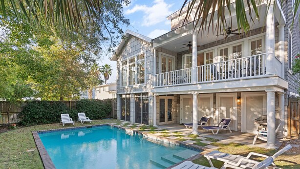 A two-story house with a swimming pool, outdoor seating, and a balcony. - Shore am Happy located at the 8th Street Beach Entrance, sleeps 12 w/ large Pool (Saint Simons Island)
