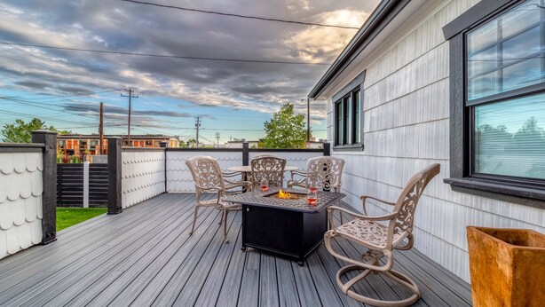 En terrasse med et bord, stole, et bålsted og udsigt til byens skyline.