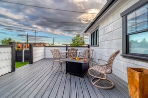 Una terraza con una mesa y sillas, un hogar para fuego y vistas del horizonte urbano.