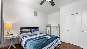 Un dormitorio con cama, mesita de noche, lámpara, cómoda y ventilador de techo.