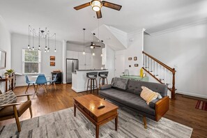 A modern living room with a sofa, coffee table, and a dining area with chairs. - Fells Point - Close to Attractions (Baltimore)