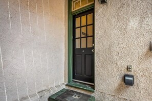 A textured wall with a black door and a small step leading to a doorbell. - Fells Point - Close to Attractions (Baltimore)