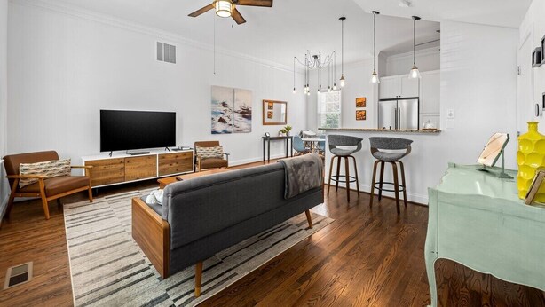 A modern living room with a sofa, TV, and dining area.