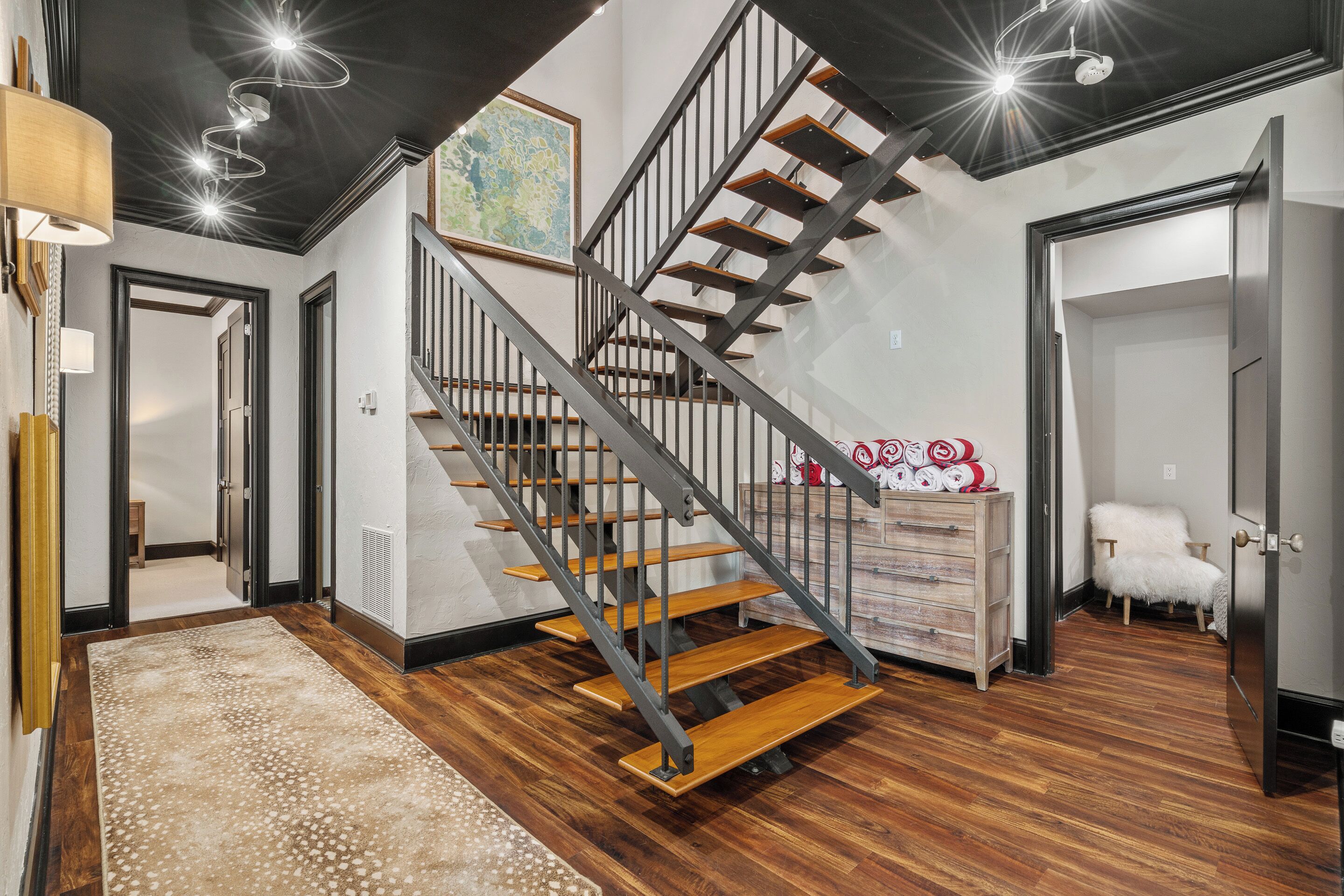 A modern staircase with wooden steps and metal railings, leading to an upper floor.