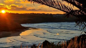 Un coucher de soleil sur une rivière, avec en arrière-plan une côte lointaine.