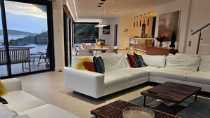 Un salon moderne doté d’un grand canapé d’angle, d’une table basse et d’un coin repas avec des chaises et une table.