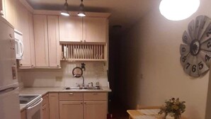 Una cocina con armarios de madera, un lavamanos y una mesa de comedor con sillas.