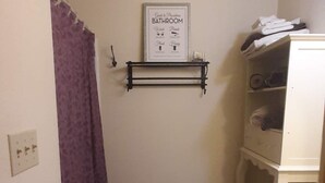 Un baño pequeño con inodoro, lavabo, cortina de ducha y estante en la pared.