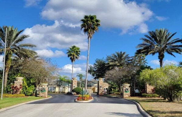 A gated entrance with palm trees and a clear sky.
