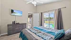 A bedroom with a bed, a TV, a dresser, and a view of a swimming pool. - Peaceful home with Pool Dog friendly 4 Bedrooms 3 Bathrooms backyard view water. (Davenport)