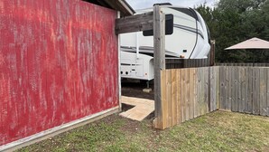 A red building with a white RV parked in front. - Large Open Range Camper sleeps up to 4 people (Dripping Springs)