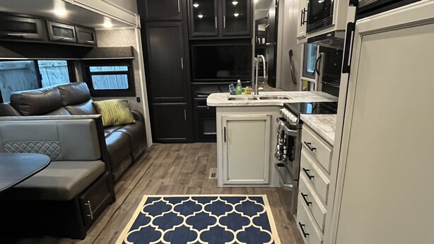 A compact kitchen with a central island, dark cabinetry, and a patterned rug. - Large Open Range Camper sleeps up to 4 people (Dripping Springs)