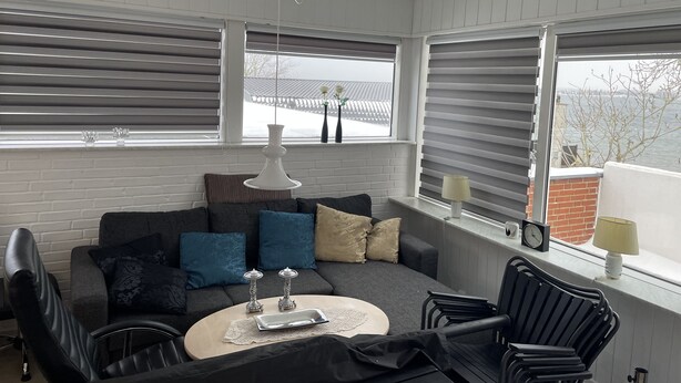 A modern living room with a grey sofa, black chairs, a round coffee table, and a white pendant light. - Fully rented accommodation with Christina as host (Gråsten)