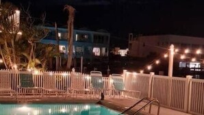 Ein Pool mit Liegestühlen und einem Zaun, umgeben von Gebäuden.