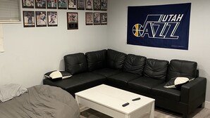 Una sala moderna con un sofá modular, una mesa de centro blanca y un tapiz con temática de baloncesto.