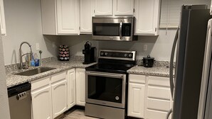 Una cocina moderna con armarios blancos, electrodomésticos de acero inoxidable y piso de madera.