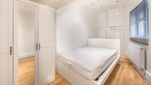 Ein kleines, modernes Schlafzimmer mit einem Bett, einem Kleiderschrank und einer Heizung.