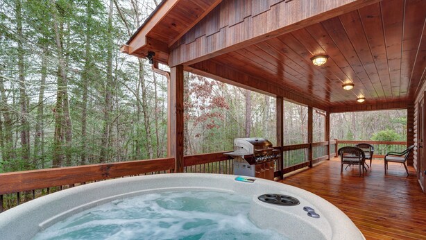 Un bain à remous sur une terrasse en bois, avec vue sur une forêt.