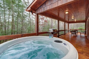 A hot tub on a wooden deck with a view of a forest. - Hemlock Haven (Blue Ridge)