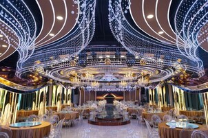 Un elegante comedor con mesas redondas, candelabros y un escenario central.