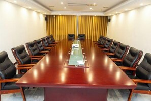 A conference room with a long table, black chairs, and a yellow curtain backdrop. - Huaxia Hotel (Handan)