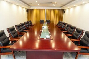 A conference room with a long table, black chairs, and a yellow curtain backdrop.
