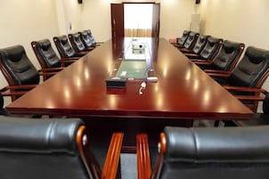 Un salón de conferencias con una mesa larga y varias sillas.