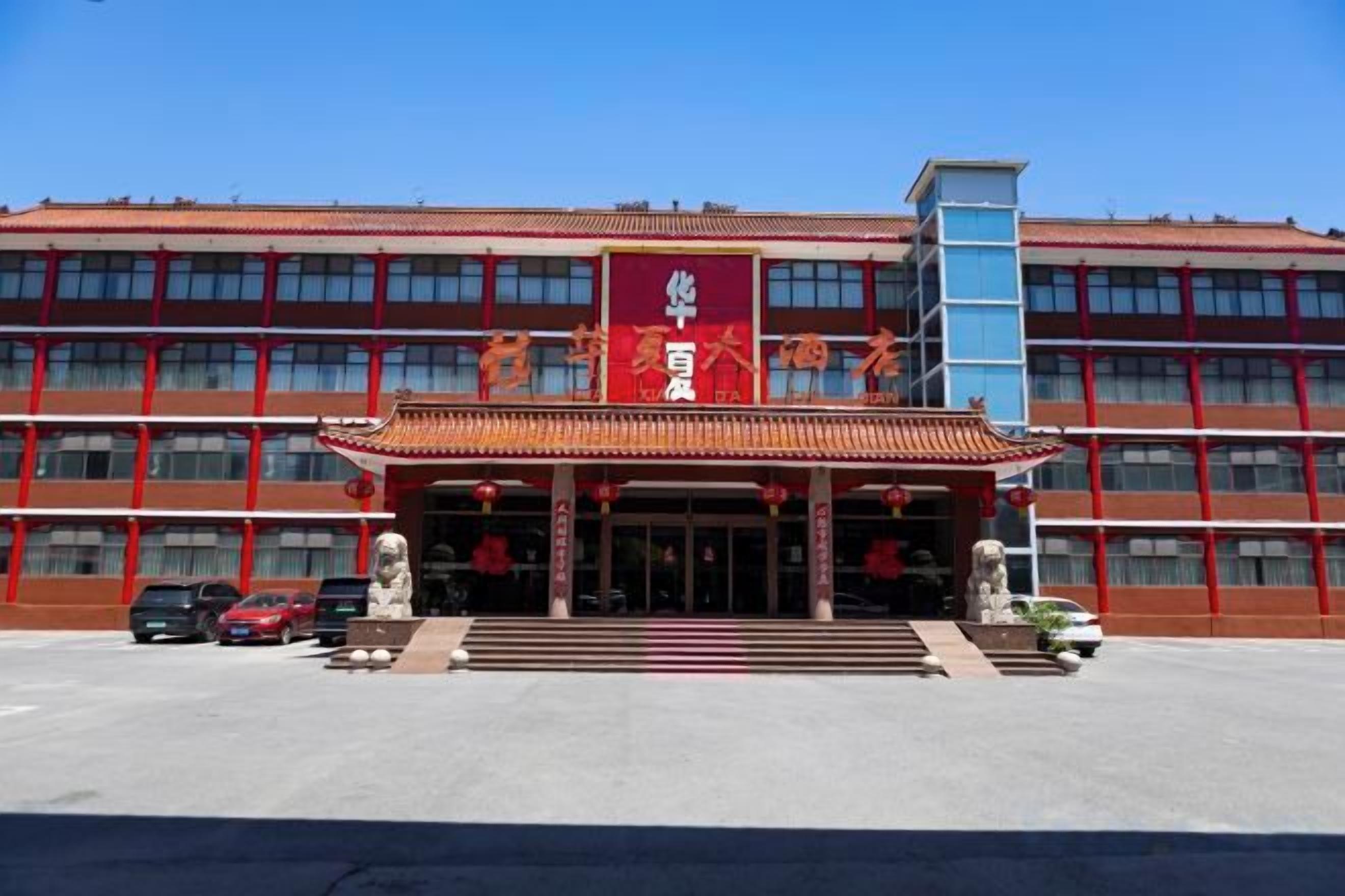 A building with a red facade, a traditional entrance with steps, and a clear blue sky.