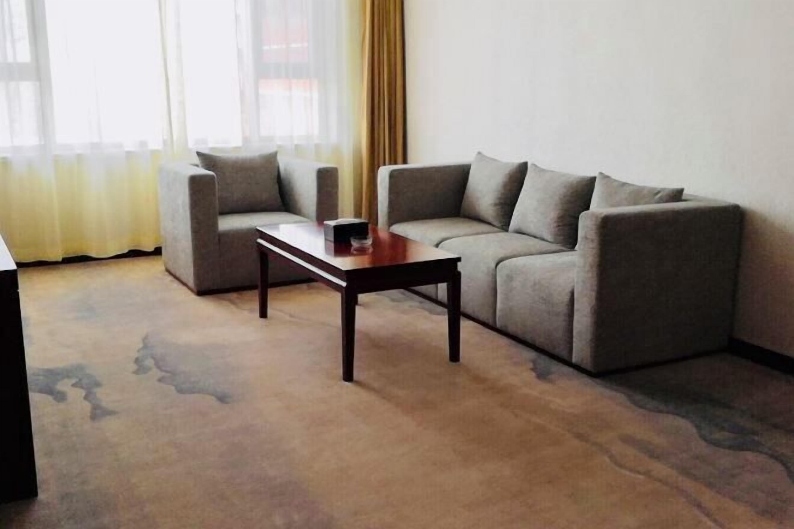 A living room with a sofa, a coffee table, and a window with curtains.