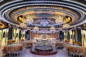 A luxurious banquet hall with a central circular table, ornate chandeliers, and clear glass tables. - Huaxia Hotel (Handan)