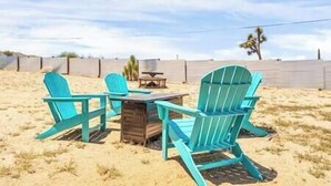 A beach setting with turquoise Adirondack chairs and a wooden table.