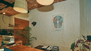 A reception desk with a wooden counter, a wall-mounted telephone, a framed artwork, and a potted plant.