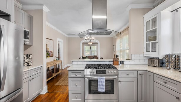 Una cocina moderna con electrodomésticos de acero inoxidable, armarios blancos y una isla central.