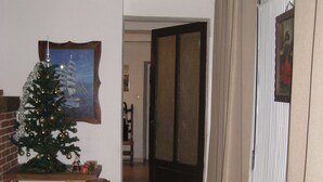 Een woonkamer met een bruine leren bank, een kerstboom en een ingelijst schilderij aan de muur.