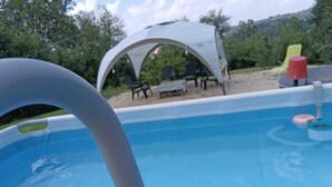 Une piscine extérieure dotée d’un auvent blanc et de chaises.