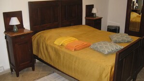 Une chambre à coucher avec un lit en bois, une table de chevet avec une lampe, une commode et un miroir.