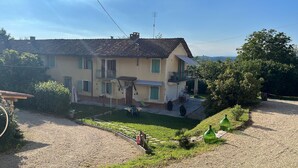 Une maison à deux étages avec un balcon, un petit jardin et une allée gravillonnée.