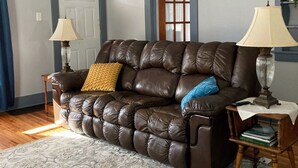 A living room with a brown leather sofa, two lamps, a patterned rug, and a door with a window.
