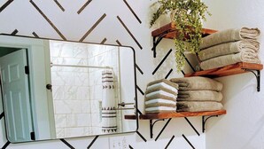 A bathroom with a black vanity, a white sink, a mirror, a toilet, and a towel rack with towels.