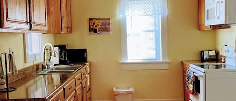 A kitchen with wooden cabinets, a sink, a microwave, and a stove.