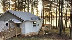A small cabin with a wooden deck and a staircase leading to a porch. - Nice cottage located on Lake Sinclair.   Lots of room with great views (Milledgeville)