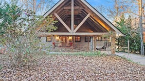 A log cabin with a triangular roof and a covered porch. - Lake Front, Beautiful views, Gentle slope to Lake, Hot tub, Close to Downtown. (Morganton)