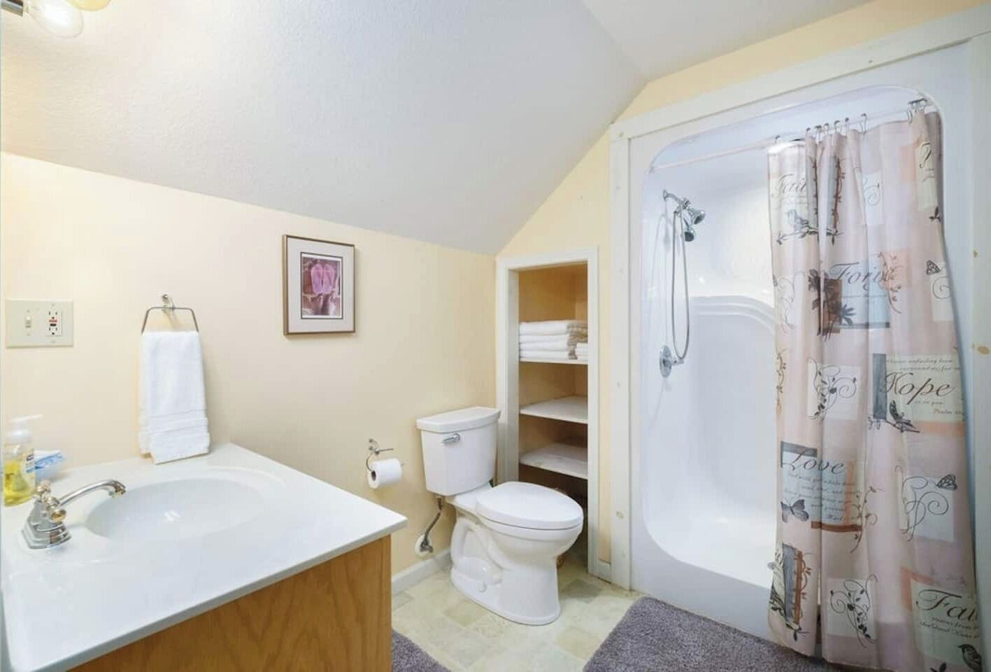 A bathroom with a white sink, toilet, and bathtub. There is a towel rack and a framed picture on the wall.