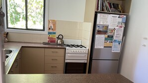 A kitchen with a gas stove, a refrigerator, and a window with blinds. - Fantastic enclosed outdoor area, fully fenced, close to shops, Eurong Beach (Eurong)