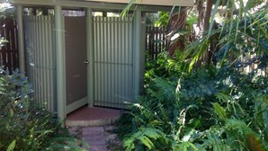 A small, enclosed outdoor structure with a metal door and a roof, surrounded by dense foliage. - Fantastic enclosed outdoor area, fully fenced, close to shops, Eurong Beach (Eurong)
