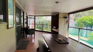 A spacious balcony with a wooden bench, a table, and a view of a garden. - Fantastic enclosed outdoor area, fully fenced, close to shops, Eurong Beach (Eurong)