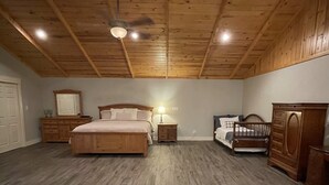 Ein Schlafzimmer mit einem großen Bett, zwei Nachttischen, einem Schminktisch und einem Deckenventilator.